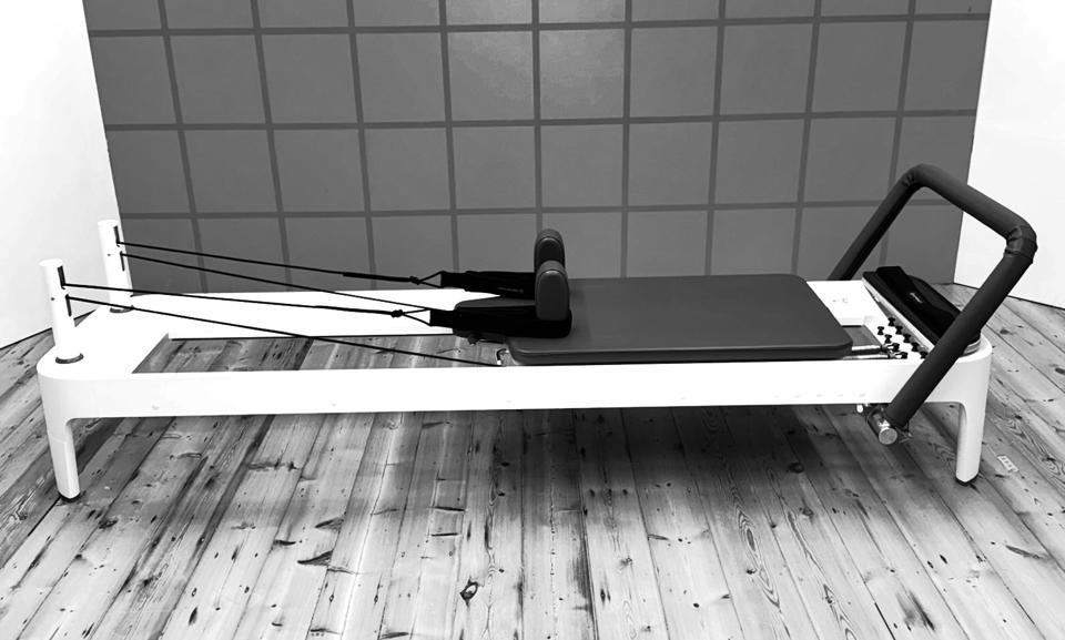 A white reformer on the studio boards against a grey grid wall