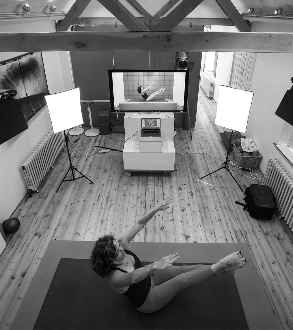 Caroline in a teaser on a mat between two softbox lights, filming a Zoom class from the studio